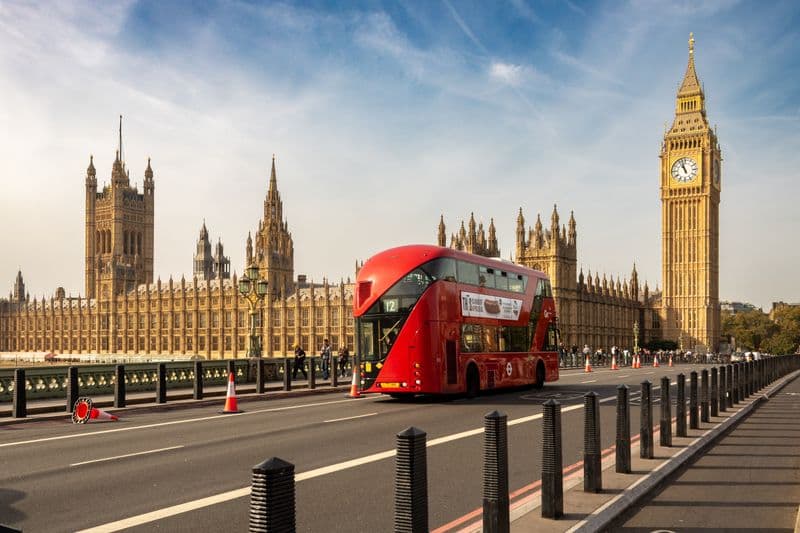 A red double-decker bus passing Elizabeth Tower, London